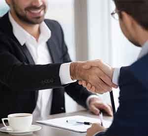 Two professionals shaking hands at a meeting.