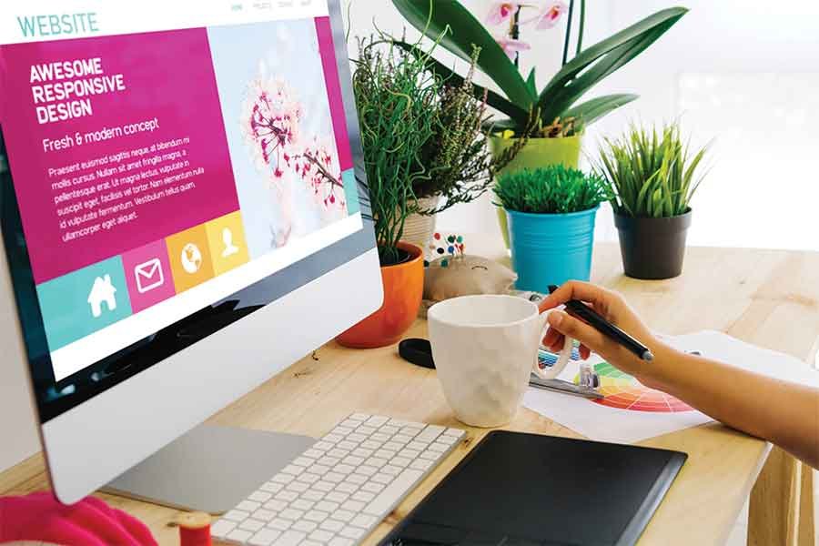 Person designing on computer at desk with plants. - Restoration Website
