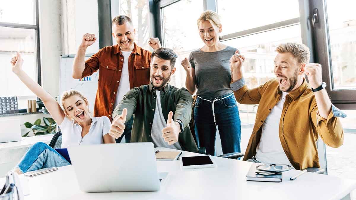 Team celebrating success with a laptop